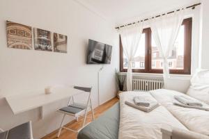 a white room with a bed and a desk and a table at Gemütliches Apartment Neustadt in Bremen