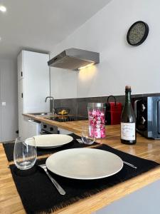 una mesa con dos platos blancos y una botella de vino en Bienvenue chez Tom, en Lamballe