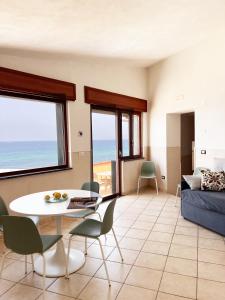 a living room with a table and chairs and the ocean at Residenza Fontanelle-Beach Resort in Santa Maria di Castellabate