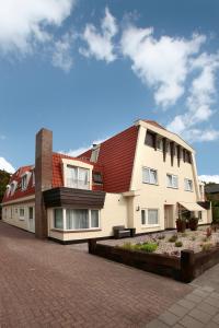 een gebouw met een rood dak op een bakstenen weg bij Hotel Zeerust Texel in De Koog