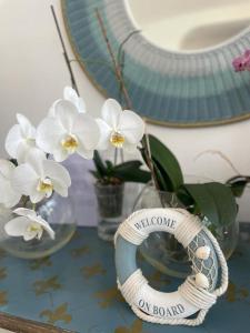 una mesa con un jarrón con flores blancas y un espejo en Hotel Mediterraneo, en Lido di Latina