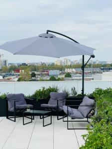 eine Terrasse mit Stühlen, einem Tisch und einem Sonnenschirm in der Unterkunft Bel Appartement avec Terrasse privée 86m2 in Noisy-le-Sec