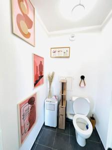 een badkamer met een toilet en foto's aan de muur bij Bel Appartement avec Terrasse privée 86m2 in Noisy-le-Sec