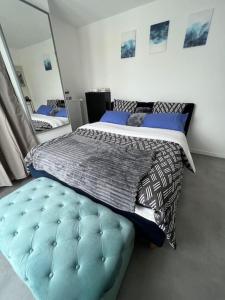 een slaapkamer met een groot bed met een blauwe poef bij Bel Appartement avec Terrasse privée 86m2 in Noisy-le-Sec