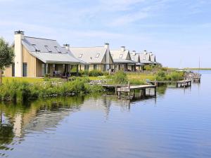 a row of houses on the shore of a lake at Modern design lodge on the water located on a holiday park in a national park in Tholen