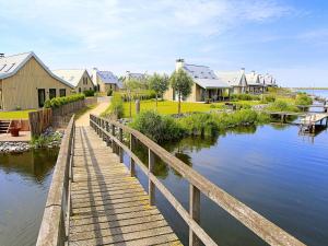 a wooden bridge over a body of water with houses at Modern design lodge on the water located on a holiday park in a national park in Tholen