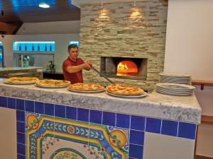 un hombre está sirviendo pizzas en un horno de pizza en Detached chalet with AC, in a natural park on the coast, en Baia Domizia