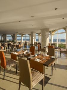 a restaurant with wooden tables and chairs and windows at AP Oriental Beach - Adults Friendly in Portimão