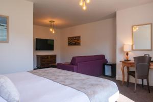 a hotel room with a bed and a chair and a desk at Domaine du Limonay, The Originals Collection in Saint-Méloir-des-Ondes