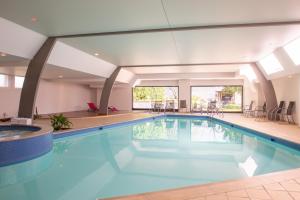 a large swimming pool in a building with at Domaine du Limonay, The Originals Collection in Saint-Méloir-des-Ondes