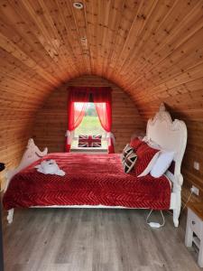 ein Schlafzimmer mit einem roten Bett in einem Holzzimmer in der Unterkunft Thompson Hall Retreat in Thompson