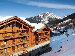 a log cabin in the snow with mountains in the background at Modern apartment near the ski lift in an authentic village in Sainte-Foy-Tarentaise