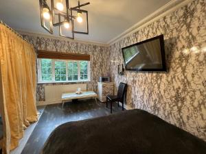1 dormitorio con 1 cama y TV en la pared en The Caduceus- Residence en Chertsey