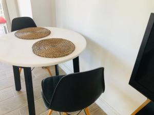 une table blanche avec deux chaises à côté d'un mur dans l'établissement Apartamento playa, à Arenys de Mar