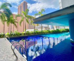 a large swimming pool with blue water and palm trees at Taragon Condominiums- KL in Kuala Lumpur