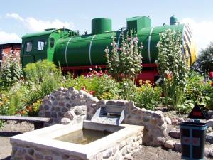 un giardino con un treno verde sullo sfondo di zz_Lokschuppen Pasewalk-Erlebnisübernachtung im Schlafwagen a Pasewalk