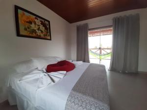 a bedroom with a white bed and a window at POUSADA ACONCHEGO CHAPADA in Alto Paraíso de Goiás