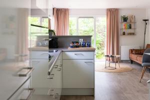 a kitchen with white cabinets and a living room at Lodge Boomklever Nunspeet Veluwe in Nunspeet