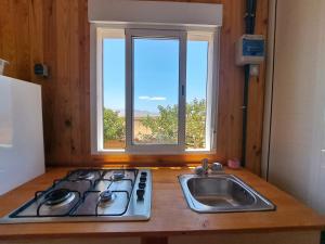 cocina con fogones, fregadero y ventana en Tiny house camión fijo en Islas Canarias en Triquivijate