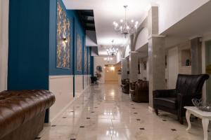 un largo pasillo con paredes azules y sillas de cuero en White Rock Castle Suite Hotel & SPA, en Balchik