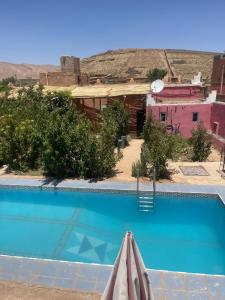 a swimming pool in front of a pink house at Riad Bouchra in Tamtetoucht