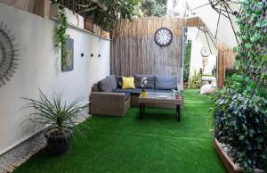 a garden with a couch and a clock on the wall at צימר פרטי בבוגרשוב VIp אופציה לחניה in Tel Aviv