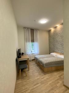 a bedroom with a bed and a desk with a television at Neiroprakse Mini Hotel in Daugavpils