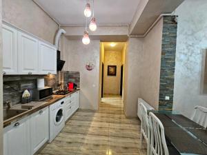 a kitchen with white cabinets and a dining table at Monaco Summerland Apartments in Mamaia