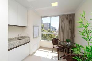 cocina y comedor con mesa y ventana en Aluguel Apartamento 2 quartos c/ 1 suíte | Bombas/SC, en Bombinhas