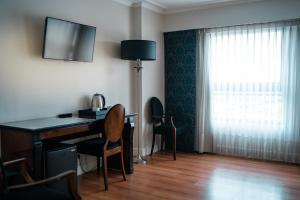 a room with a desk with a lamp and a window at Amérian Executive Córdoba Hotel in Córdoba