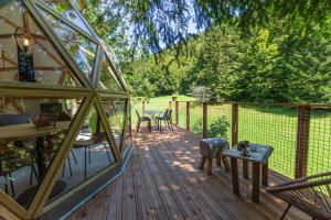 una gran terraza de madera con mesa y sillas. en Dôme panoramique tout confort au cœur du Vercors, en Autrans