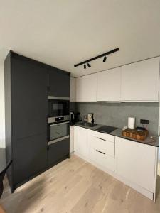 a kitchen with white cabinets and black appliances at Modern & Compact 1BD Flat - Caledonian Road in London