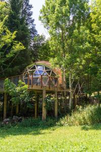 eine Holzterrasse mit einem Pavillon im Gras in der Unterkunft Dôme panoramique tout confort au cœur du Vercors in Autrans