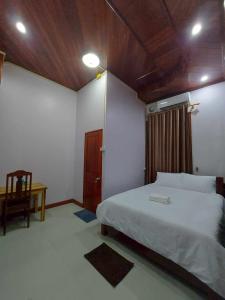 a bedroom with a white bed and a wooden ceiling at Inthavong Hotel/Guest House in Vang Vieng