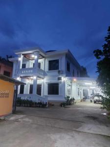 una grande casa bianca di notte con luci di Inthavong Hotel/Guest House a Vang Vieng