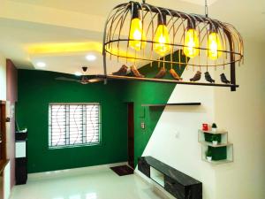 Habitación con una pared verde y una lámpara de araña. en ASSHAPPYSTAYINN HOTEL, en Tiruchchirāppalli