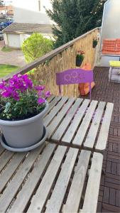 un banco de madera sentado junto a una maceta de flores en Appartement cosy, en Dijon