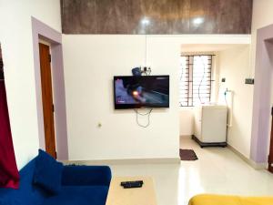 a living room with a tv on a wall at ASSHAPPYSTAYINN HOTEL in Tiruchchirāppalli