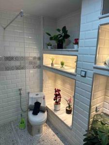 ein Badezimmer mit WC und Pflanzen auf Regalen in der Unterkunft Mira loft in Bejaïa