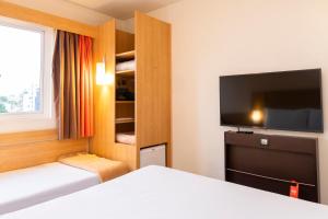 a hotel room with a bed and a flat screen tv at ibis Porto Alegre Moinhos de Vento in Porto Alegre