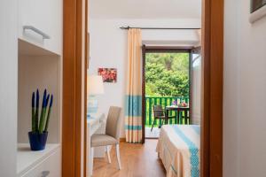 a bedroom with a bed and a desk and a balcony at Hotel Dei Pini in Alghero