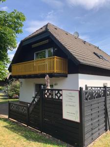 ein Haus mit einem Zaun und einem Schild davor in der Unterkunft Ferienhaus Moni mit 2 separaten Wohnungen am Silbersee in Frielendorf