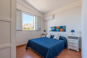 una camera con un letto blu e una finestra di Casa Lia e Nino a San Vito Lo Capo a San Vito lo Capo