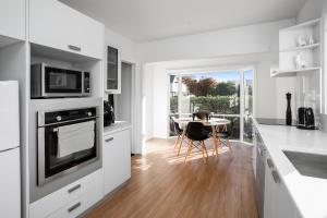 クライストチャーチにあるQuality City Appartmentのキッチン(白いキャビネット、テーブル、椅子付)