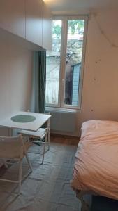 布洛涅－比揚古的住宿－Cozy Studio*Near Paris*Ideal Couple，一间卧室配有一张床、一张桌子和一个窗户。