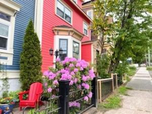 a red house with pink flowers and a fence at Water Street and HarborGate Condos & Studios in St. John's