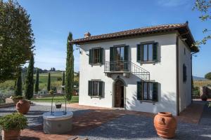 Casa blanca con persianas verdes y patio en Villa Le Gallozzole, en Quercegrossa