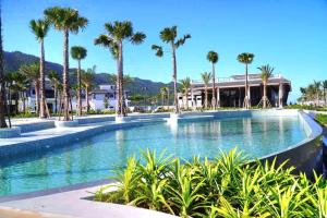 a swimming pool with palm trees and a building at LAS VEGAS HOTEL in Quang Ninh