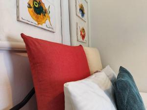 um sofá com uma almofada vermelha e algumas fotos na parede em Diva - Free Parking - Explore Center by foot - Close to Helexpo, University & Hospital em Tessalônica