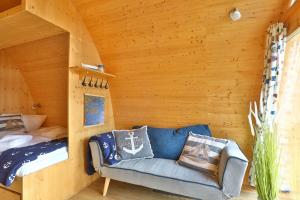 Habitación con sofá y cama en una cabaña de madera. en Hausboot Dotterbart, en Gager